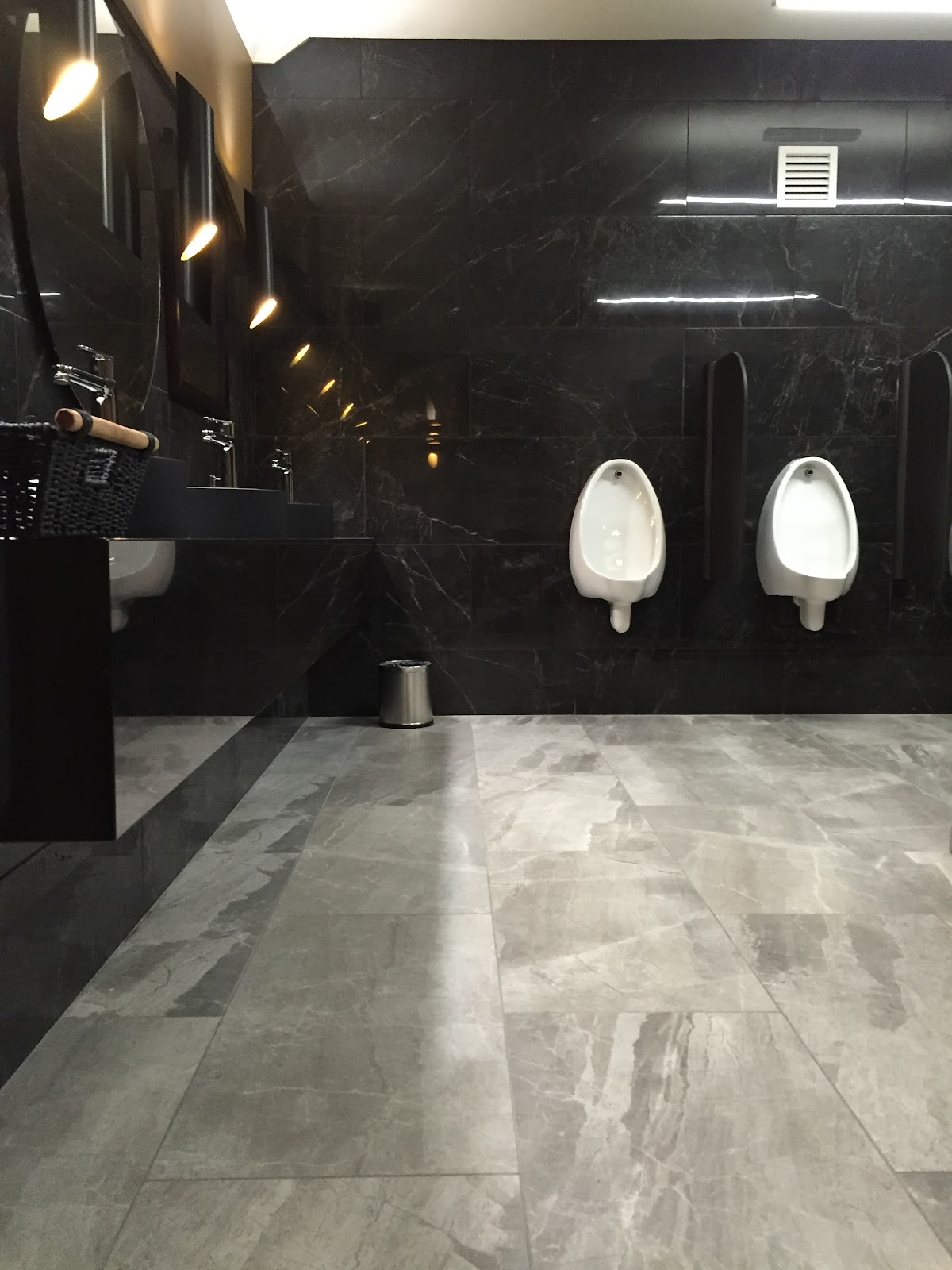 Black marble commercial washroom with a grey marble floor
